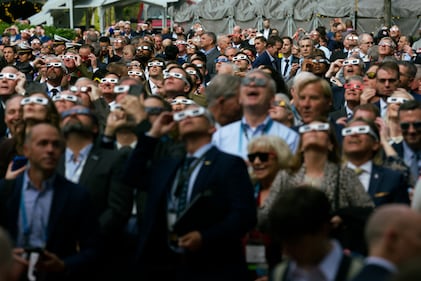 Sea-Air-Space attendees step out of the naval conference in National Harbor, Maryland, to observe the solar eclipse April 8, 2024.