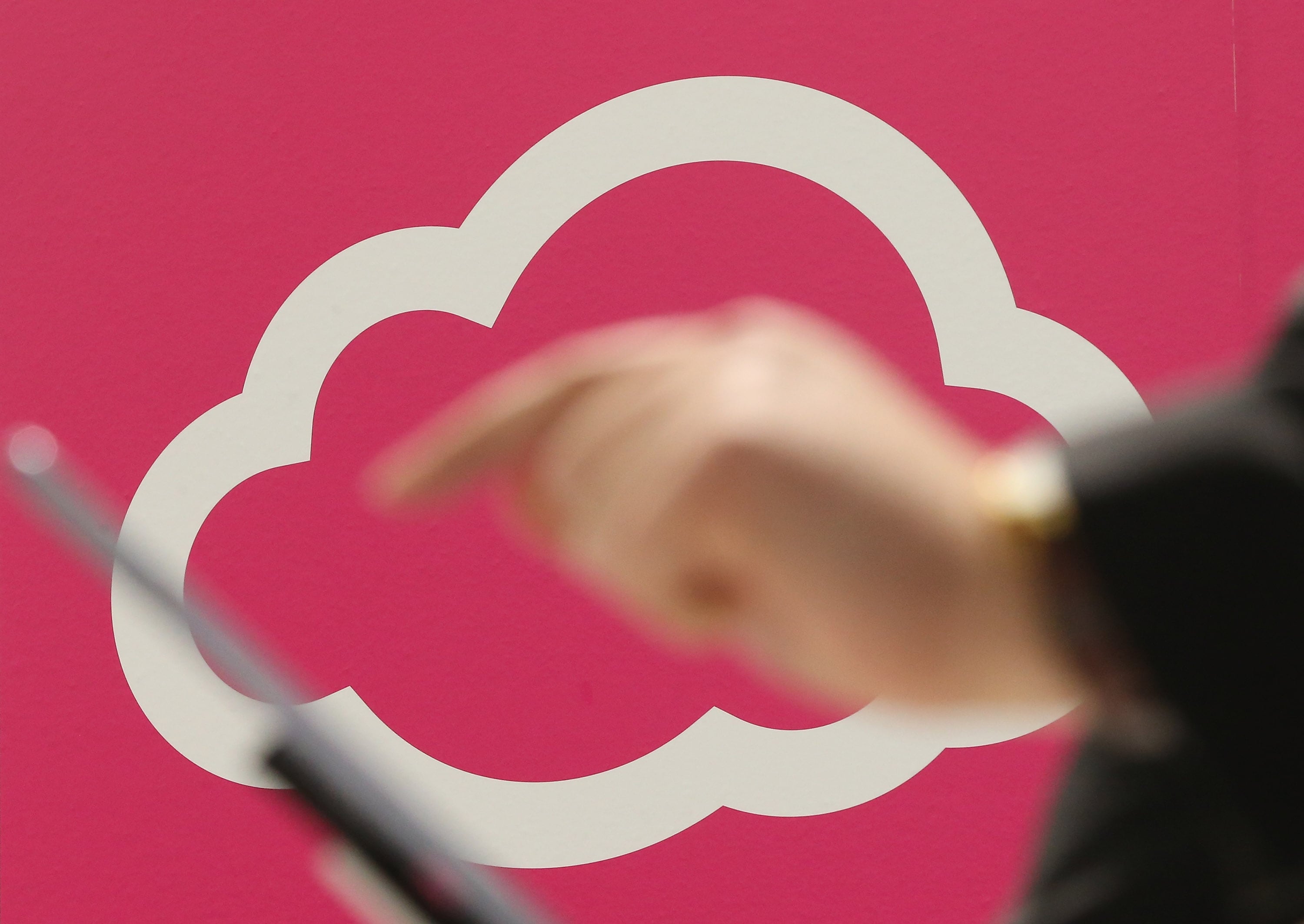 A person tries out a tablet computer next to a cloud computing and technology symbol at a trade fair in Hanover, Germany.