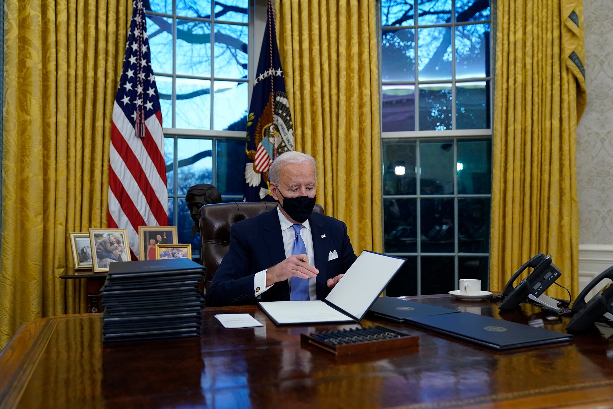 President Joe Biden signs his first executive orders in the Oval Office of the White House on Wednesday, Jan. 20, 2021, in Washington.