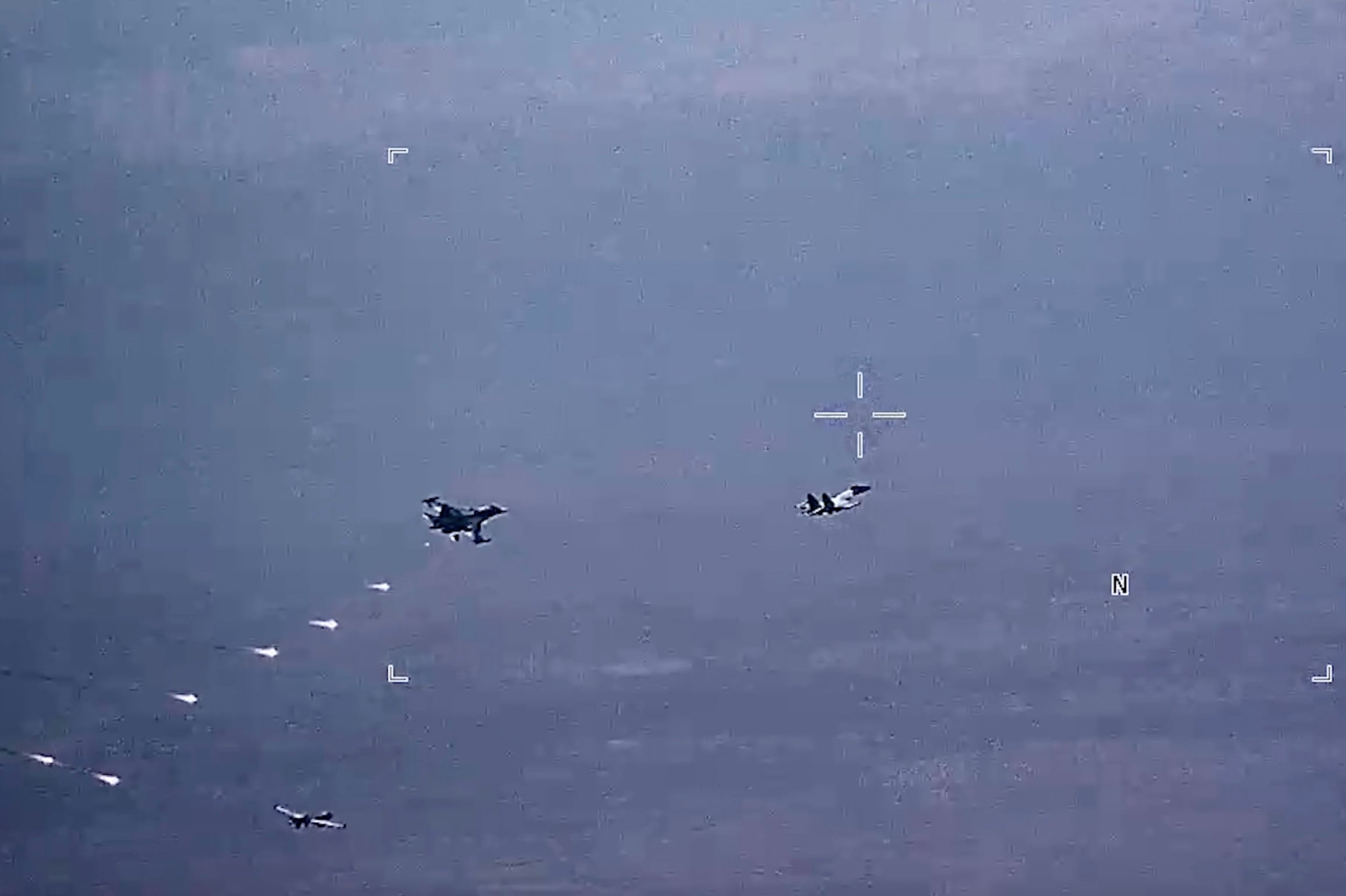 In this image from video released by the U.S. Air Force, Russian military SU-34 and SU-35 aircraft release flares in the flight path of a U.S. Air Force MQ-9 Reaper drone, lower left, on Thursday, July 6, 2023, over Syria.